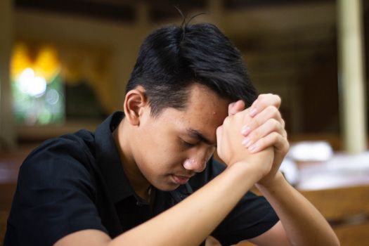特写镜头中，一名男子在室内闭眼祈祷