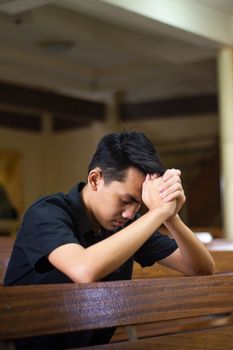 一名年轻男子在教堂里闭目深深祈祷