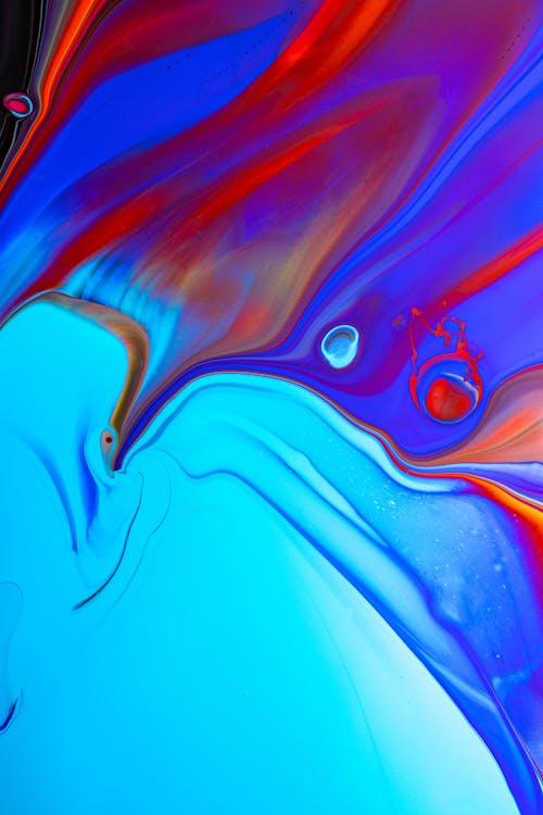From above of colorful iridescent paints flowing and mixing together as abstract background