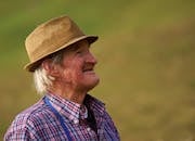 老农戴着帽子，快乐地凝视着户外，显得喜悦而朴素