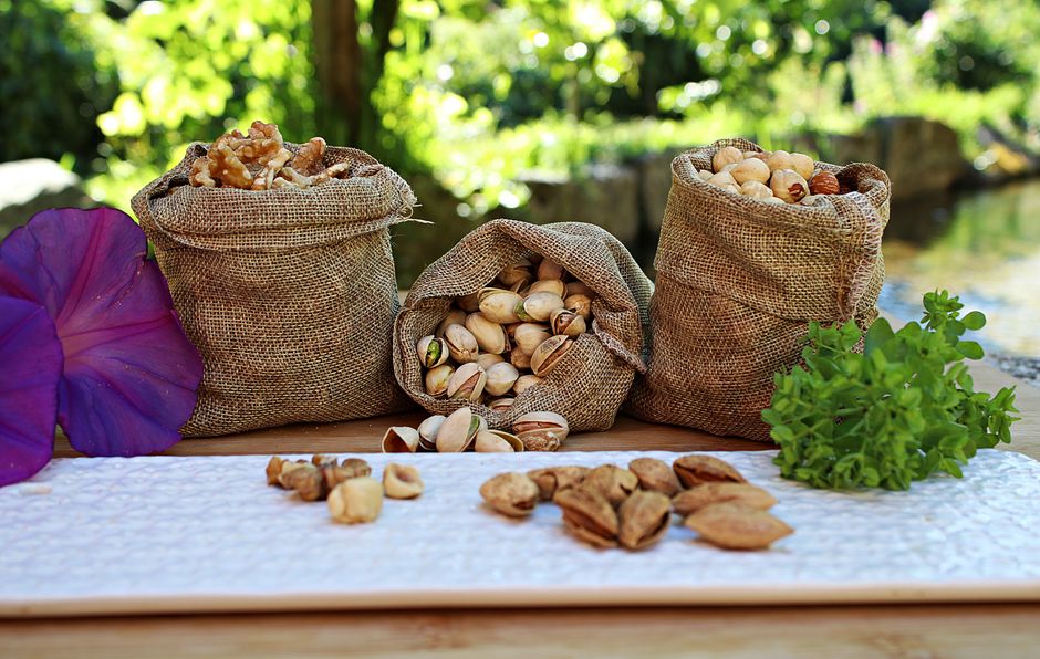 Hạt sang - bí mật chữa dạ dày của người Mông 4 Jute sacks with pistachios walnuts and peanuts placed on wooden table in park near pond on sunny day