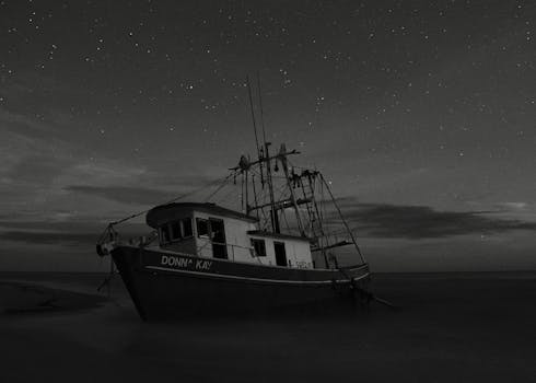 A haunting image of an abandoned fishing boat, Donna Kay, resting under a starry night sky on a Florida beach.