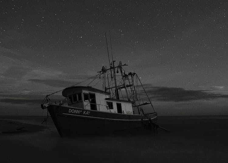 White And Black Boat On Sea Under Gray Sky