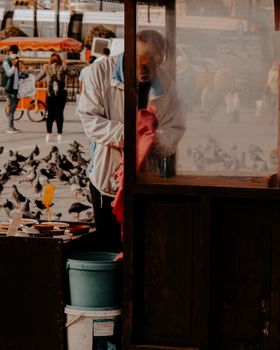 伊斯坦布尔热闹的户外市场上，一名街头小贩在摊位旁放鸽子