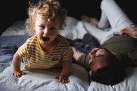 一个开朗的幼儿和父亲在室内玩耍，享受着家庭快乐的时光