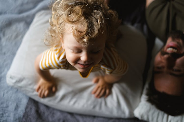 A Child Being Playful With A Parent On The Bed