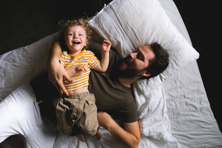 A Father And Son Lying On The Bed