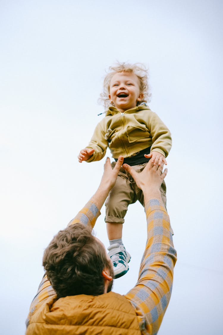 A Man Throwing His Son In The Air