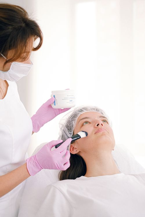 Free Beautician applying facial treatment to a patient in a modern skincare clinic setting. Stock Photo