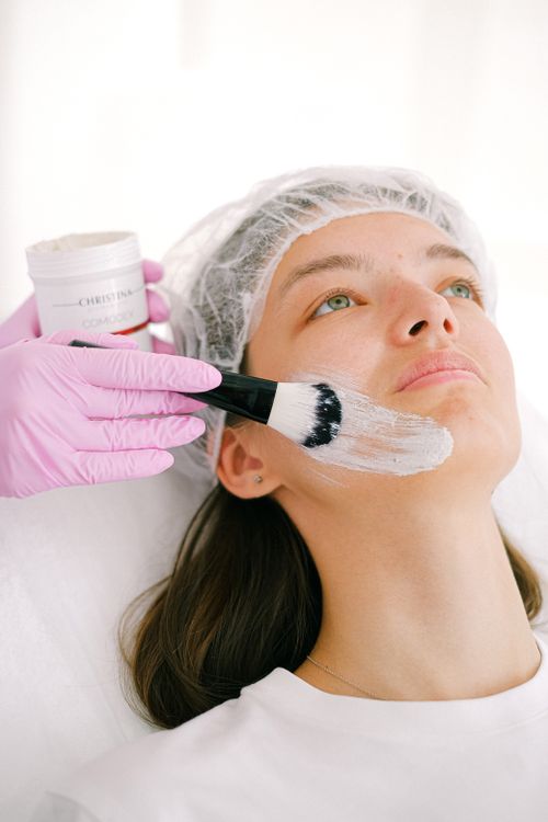 Free Close-up of a woman receiving a facial mask treatment in a spa setting. Stock Photo