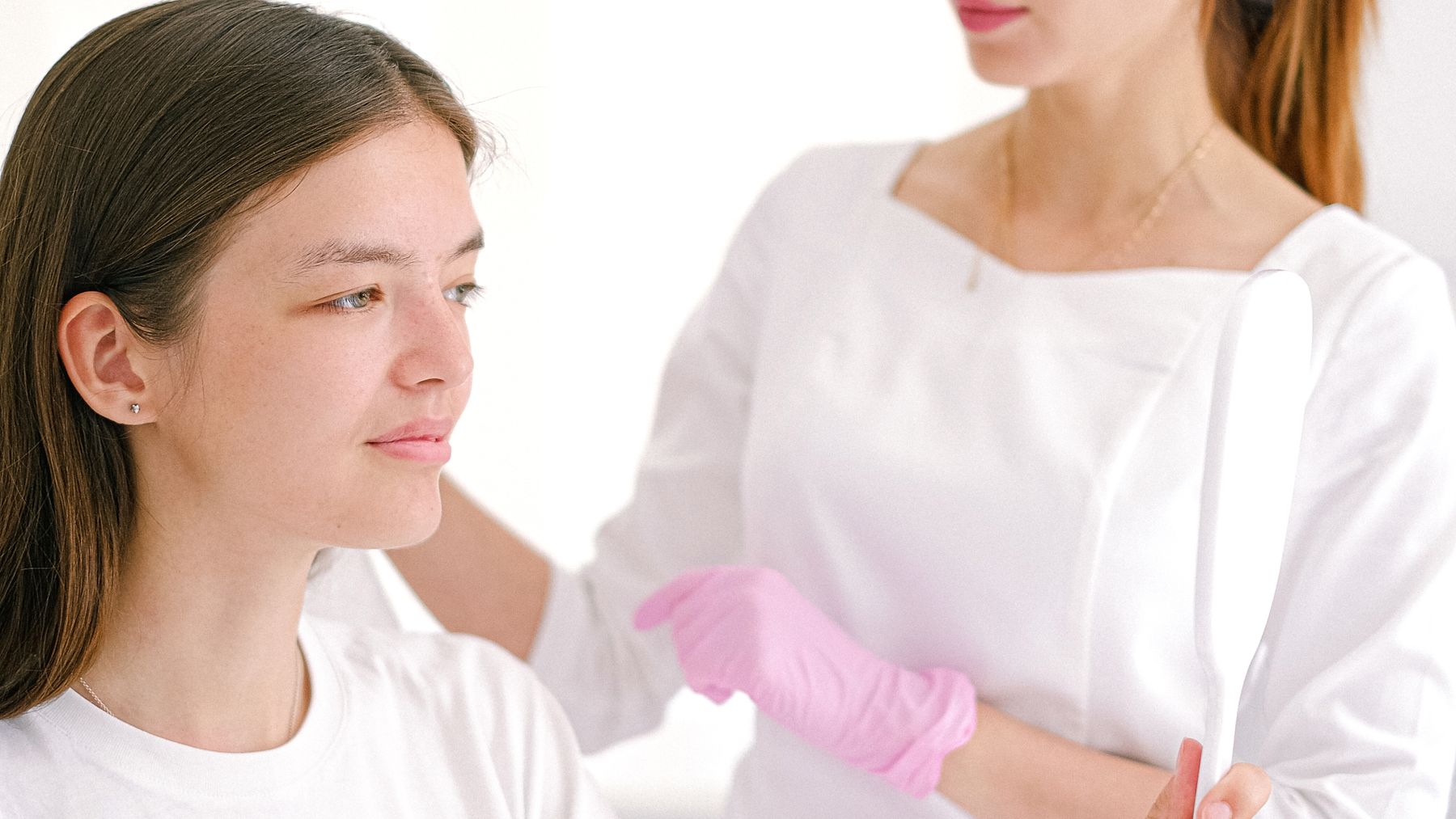 Patient discussing cosmetic concerns with a clinician while holding a mirror