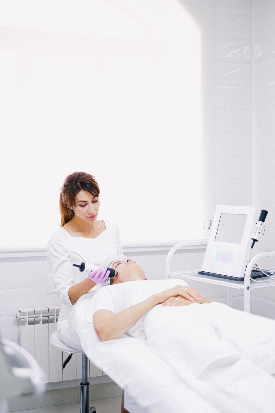 Nueva experiencia — Pago Semanal Esteticista atendiendo a una clienta con un equipo de tratamiento en un salón luminoso