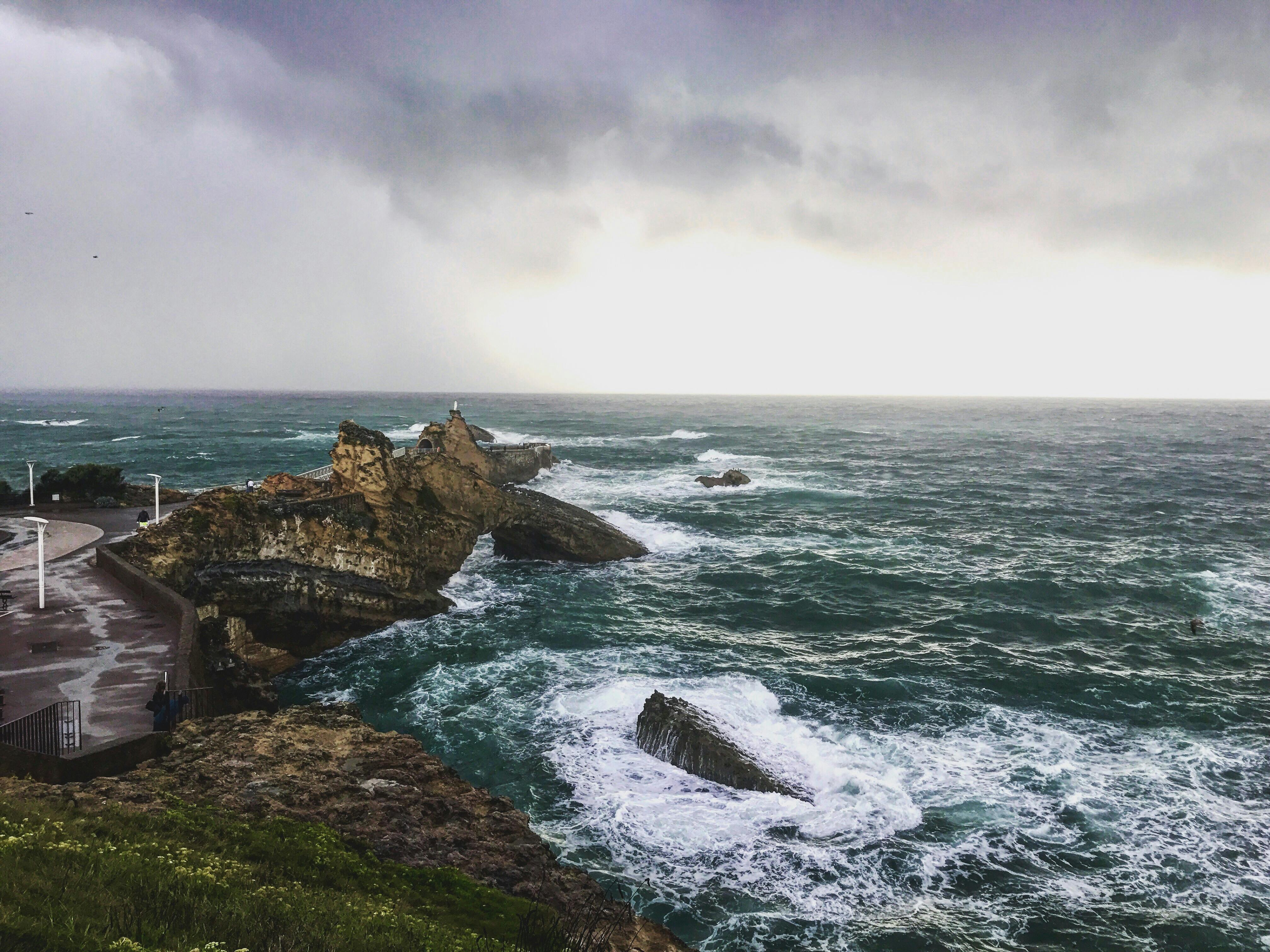 Rocky Cliff On Shore Of Wavy Sea On Overcast Day · Free Stock Photo