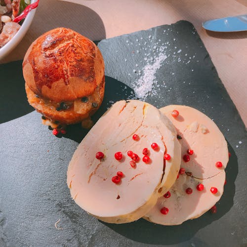 From above of delicious cut meatloaf served on black slate plate with appetizing crispy burger and decorated with pomegranate seeds