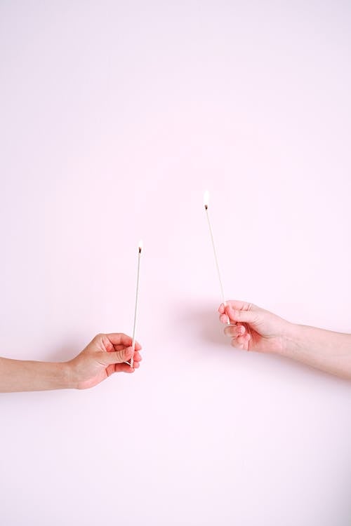 People Holding Sticks on White Surface
