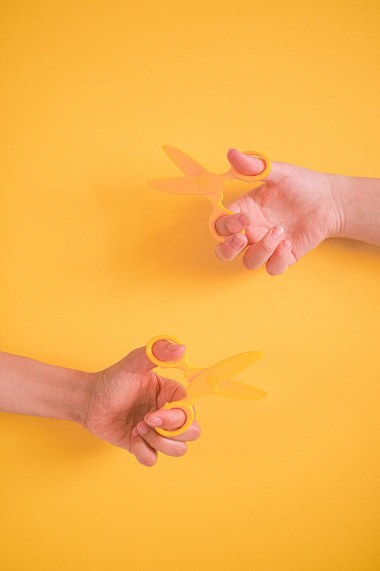 People Holding Yellow Toy Scissors