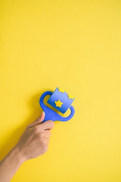Hand Holding Toy Roll on Yellow Background