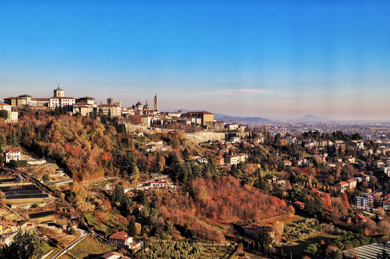 Stunning aerial capture of Bergamo, showcasing its historic architecture and vibrant autumn foliage.