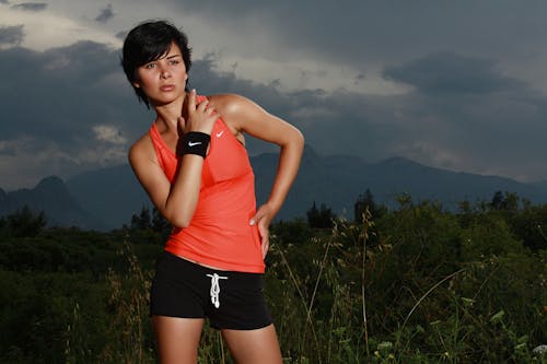 Woman in Orange Nike Tank Top Surrounded With Grasses