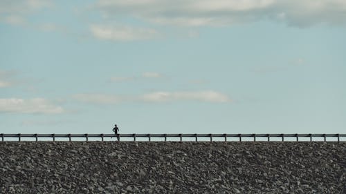 Silhouette of Person Running on the Bridge