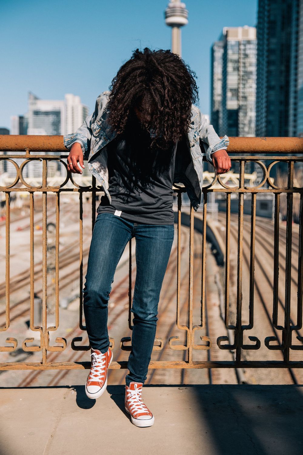 Man Leaning on Walkway Railing Above Train Tracks · Free Stock Photo