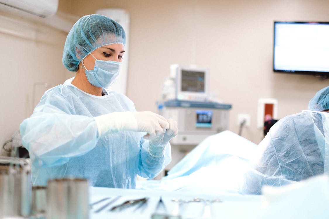 Woman in Blue Dress Shirt Wearing Blue surgical uniform and White Latex Gloves