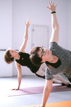 Two women engaging in a yoga session indoors, focusing on balance and flexibility.