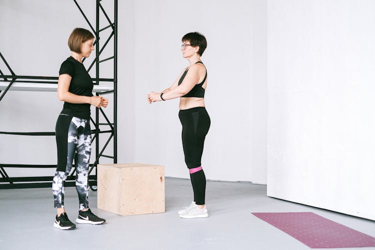 A Fitness Coach Supervising An Elderly Woman Exercise