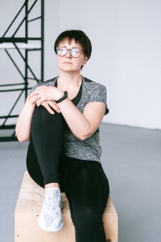 一位穿着运动服的女性自信地坐在室内，展现了健康与力量