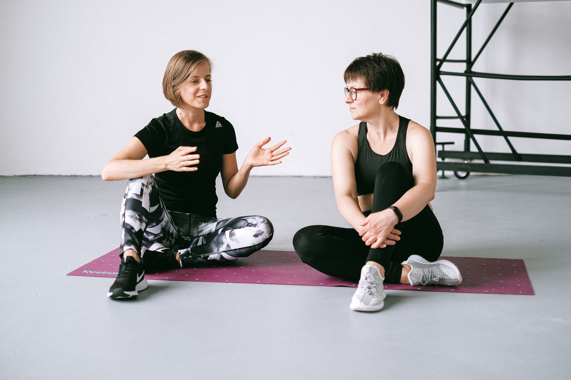 Women in Active Wear Discussing While Sitting on Purple Yoga Mat