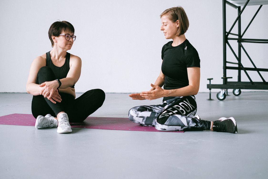 Women in Sportswear Discussing and Sitting on Purple Yoga Mat · Free ...
