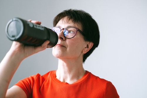 Free Caucasian senior woman in glasses drinking from a bottle, promoting active lifestyle. Stock Photo