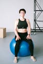 一位穿着健身服的成年女性正在室内利用稳定球进行锻炼，以保持身体强健和平衡
