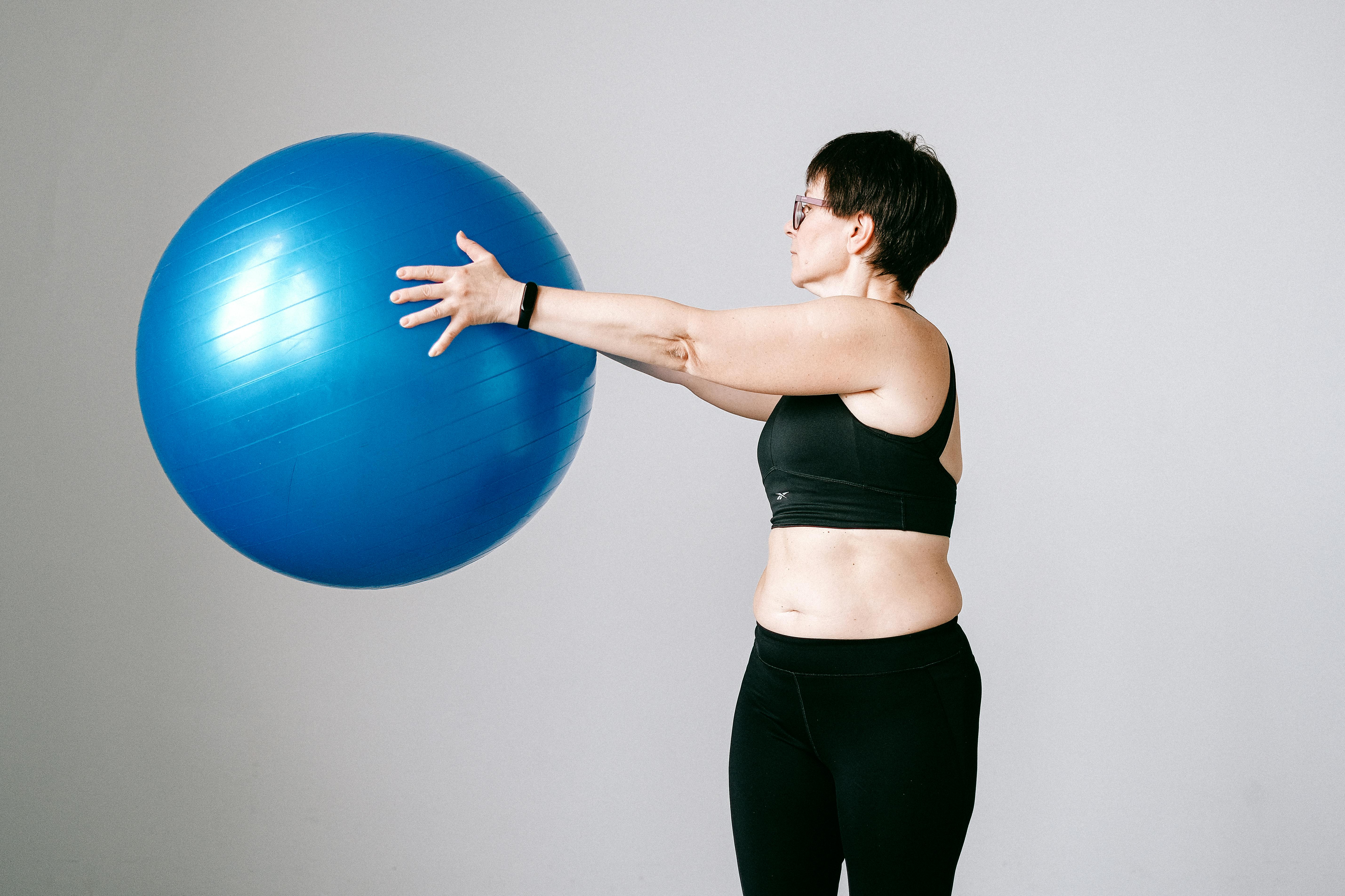 Woman holding blue exercise ball. | Photo: Pexels