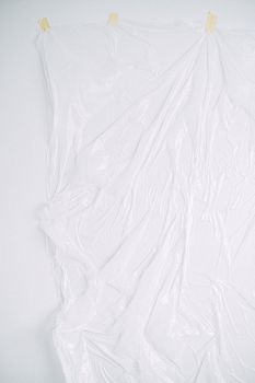 一块纹理丰富的白色塑料板贴在墙上，是极简主义背景的理想选择，并提供充足的复制空间