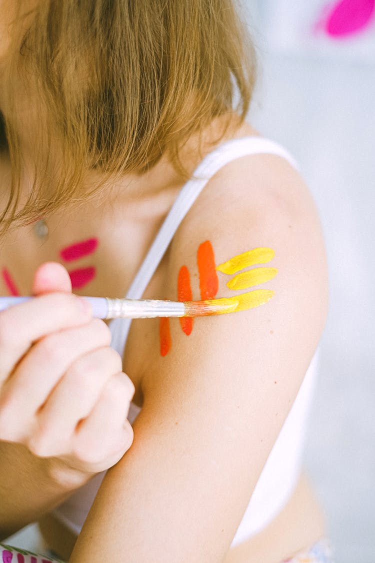 A Woman Applying Paint On Her Shoulder