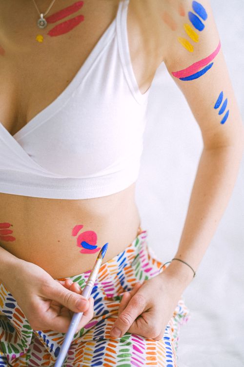 Free Creative design of colorful body paint applied to woman's skin using a brush indoors. Stock Photo