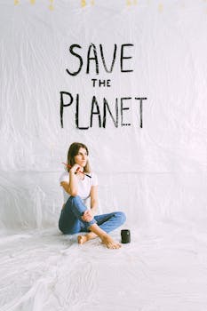 A woman artist sitting barefoot with a brush, promoting an environmental message indoors.