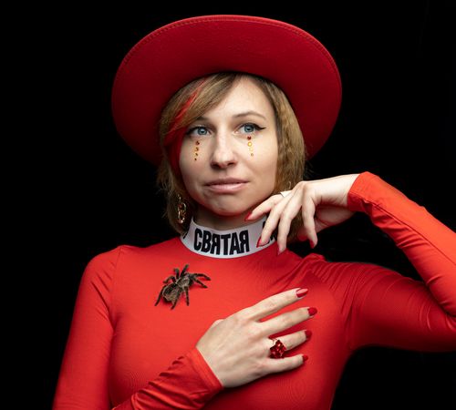 Free Cheerful young female in bright red clothing and hat with sandy hair and rhinestones under eyes looking away with smile on black background Stock Photo
