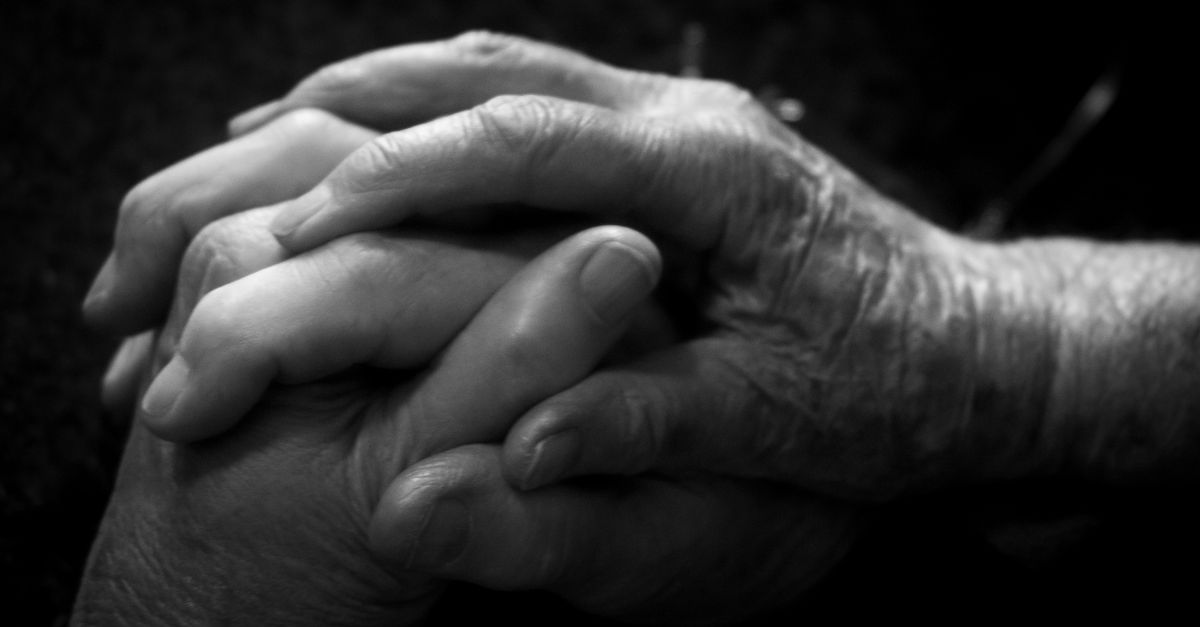 Close-up of two hands clasped together in a grayscale setting, evoking connection and care.