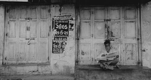 Man reading paper near decayed building