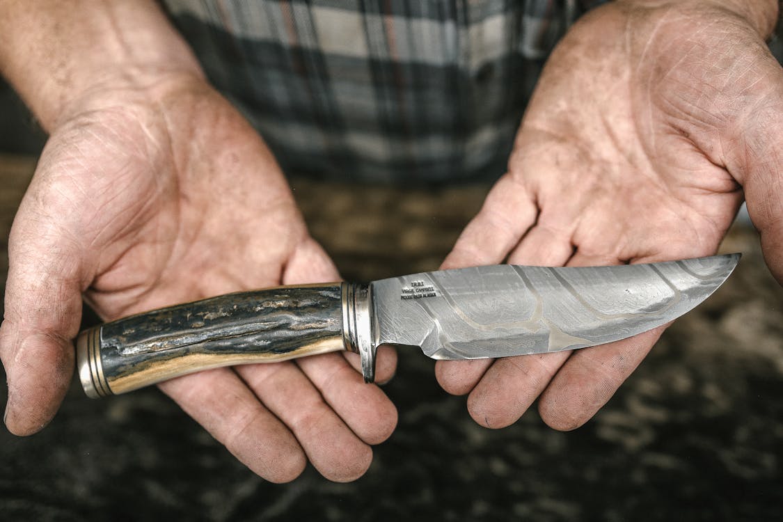 Free Hunting Knife in Hands of Unrecognizable Man Stock Photo