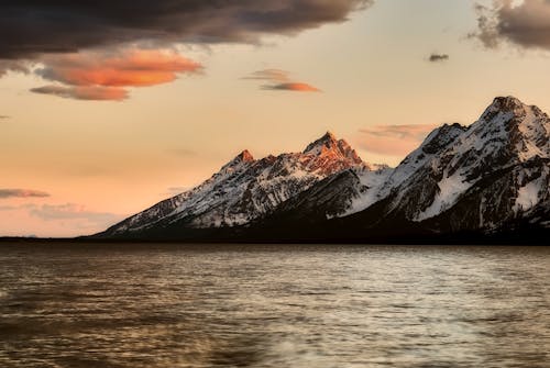 Free Black Mountain on Body of Water Under Sky Stock Photo