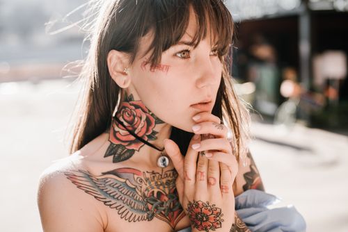 Free Close-up portrait of a tattooed woman outdoors in bright sunlight, showcasing intricate body art and expression. Stock Photo