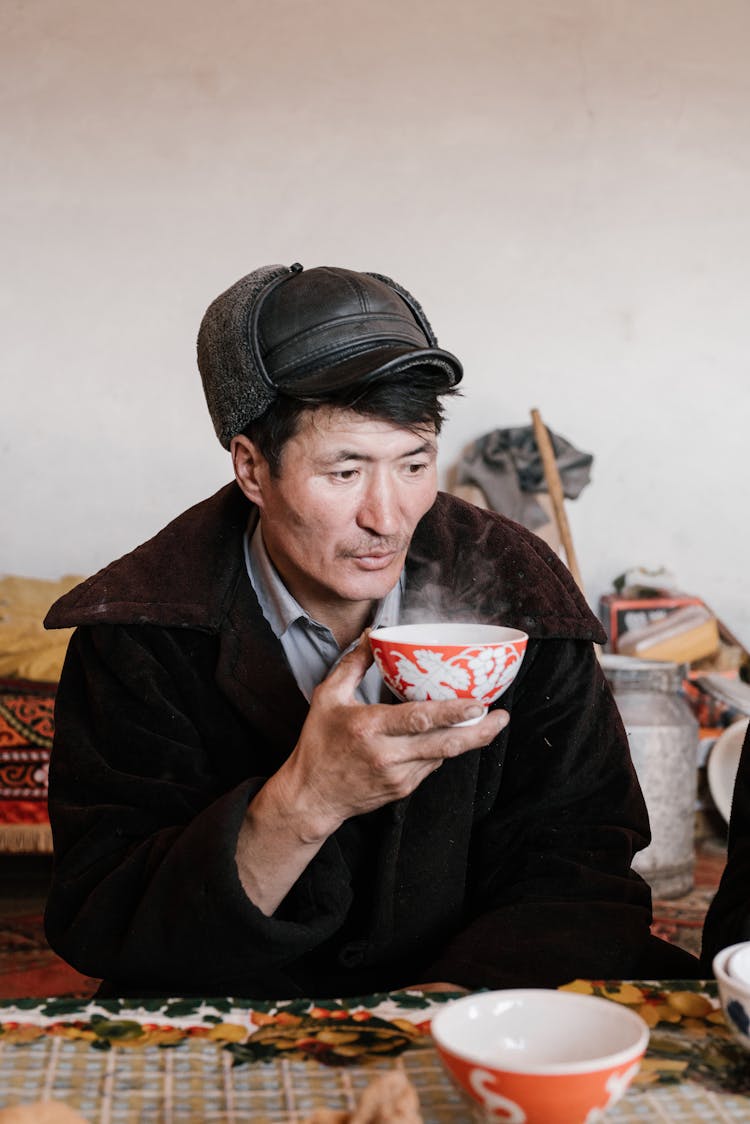 Old Man In Outerwear Drinking Tea At The Table