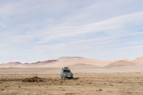 Free A 4x4 vehicle traversing remote desert landscape under a blue sky, emphasizing adventure. Stock Photo