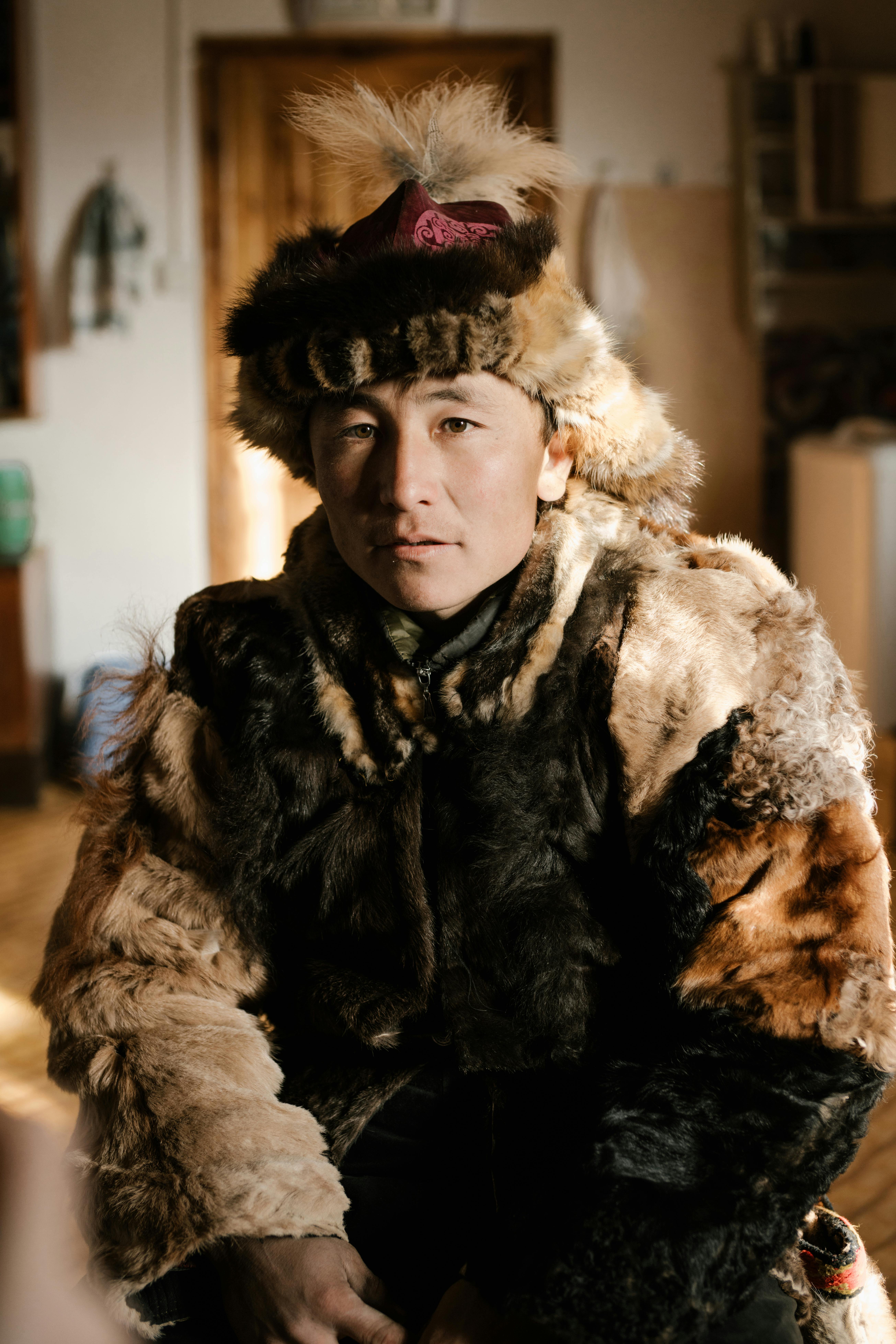 Free A portrait of a man in traditional fur clothing indoors, showcasing Mongolian cultural attire. Stock Photo