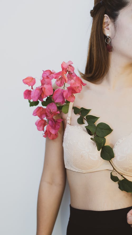 A Woman in Lace Brassiere Holding Pink Flowers