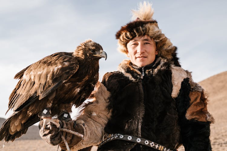 Far East Falconer With Eagle Sitting On Hand