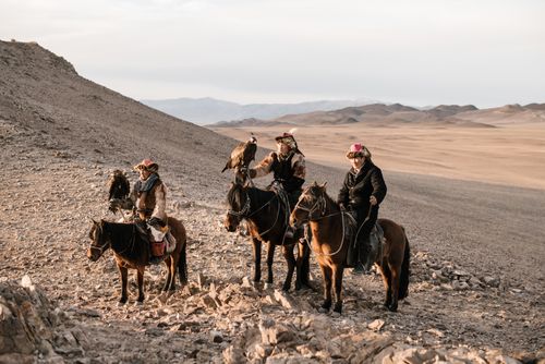 Free Three traditional eagle hunters riding horses in the arid Mongolian landscape, showcasing falconry skills. Stock Photo